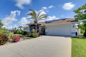 A residential house with a garage, a driveway, and a well-maintained lawn with various plants. - Patio & Grill! Canalfront Rotonda West Golf Escape (Rotonda West)