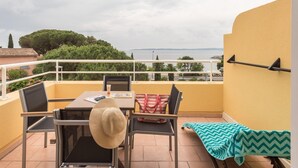 Ein Balkon mit Tisch, Stühlen, einer Streifen-Tasche und einer Decken mit Zickzackmuster.