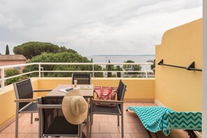 A balcony with a table, chairs, a striped bag, and a chevron-patterned blanket.