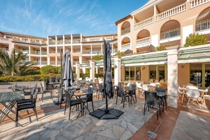 A hotel courtyard with outdoor seating, a pool, and multiple balconies. - Luxury 4-Person Riviera Sanctuary (Les Issambres)