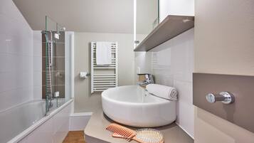 A bathroom with a glass shower enclosure, a white sink, and a towel rack.