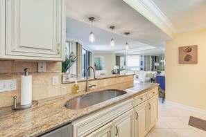 Eine Küche mit Granit-Arbeitsplatten, Spüle aus Edelstahl und Pendelleuchten.
