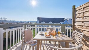Ein Balkon mit Tisch für zwei Personen, einem Stuhl und Blick auf ein Haus im Hintergrund.