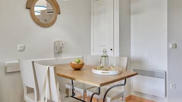 A dining area with a wooden table, white chairs, a mirror, and a white door.