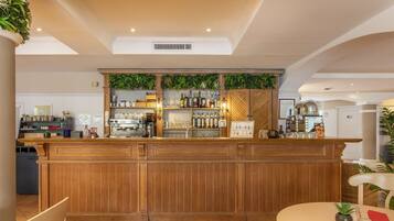 Un espace bar avec un comptoir en bois, des étagères remplies de bouteilles et une table à manger avec des chaises.