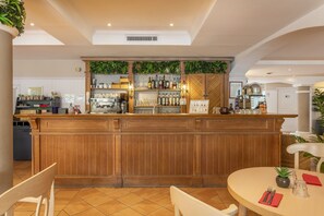 Eine Bar mit Holztresen, Regalen voller Flaschen und einem Esstisch mit Stühlen.