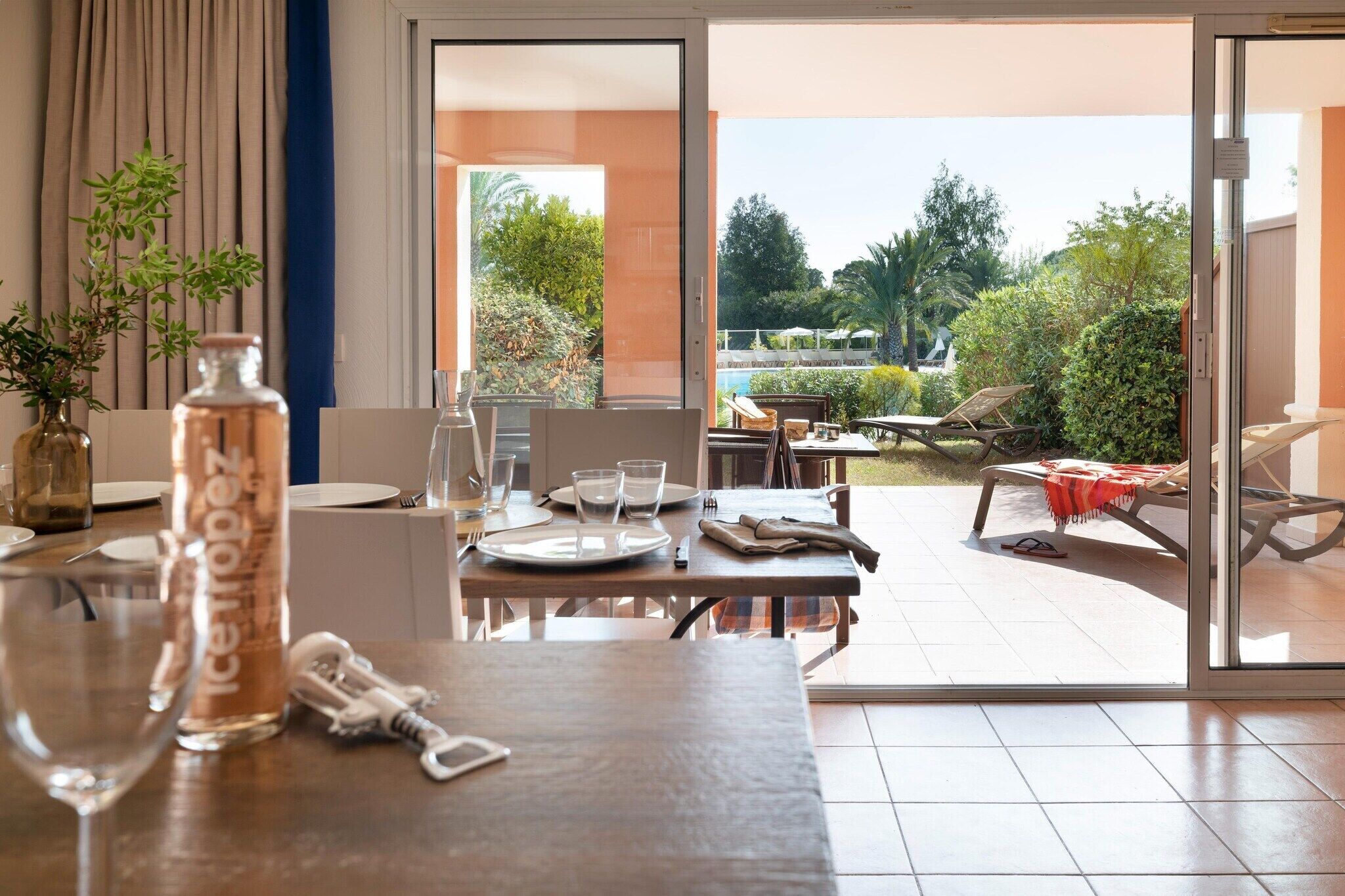 A dining area with a table set for two, a bottle of water, and a wine glass.