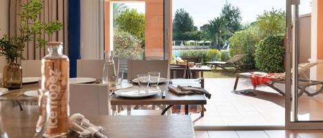 A dining area with a table set for two, a bottle of water, and a wine glass.