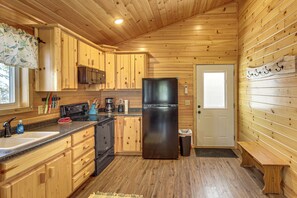 A compact kitchen with wooden cabinets, a stainless steel refrigerator, a microwave, and a sink.