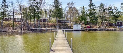 A wooden dock leading to a row of cabins by a lake.