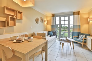 Ein modernes Wohnzimmer mit Essbereich, einer Couch und Blick ins Freie.