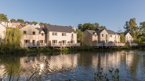 A row of modern houses with balconies, a calm lake, and a clear sky.