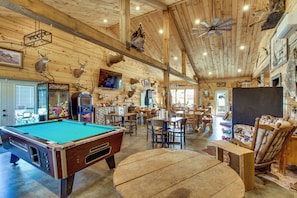 Un intĂ©rieur en bois comprenant une table de billard, un coin repas et diffĂ©rentes tĂȘtes dâanimaux montĂ©es au mur.