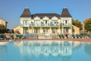 Un hotel con piscina, varios balcones y un estilo arquitectónico tradicional.