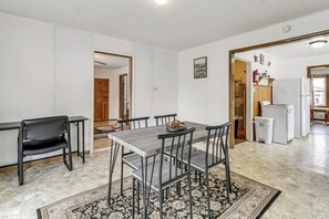 Un comedor con mesa y sillas, un tapete y una cocina al fondo.