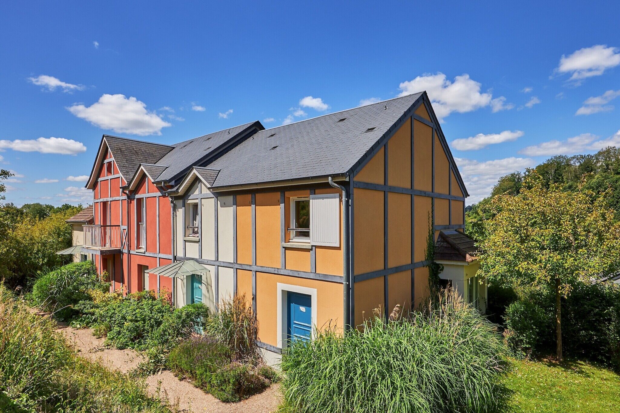 Ett hus med flera våningar, ett sluttande tak, en balkong och en trädgårdsdel.