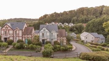 Un quartiere residenziale con case tradizionali a graticcio, una strada curvo e una collina boscosa sullo sfondo.