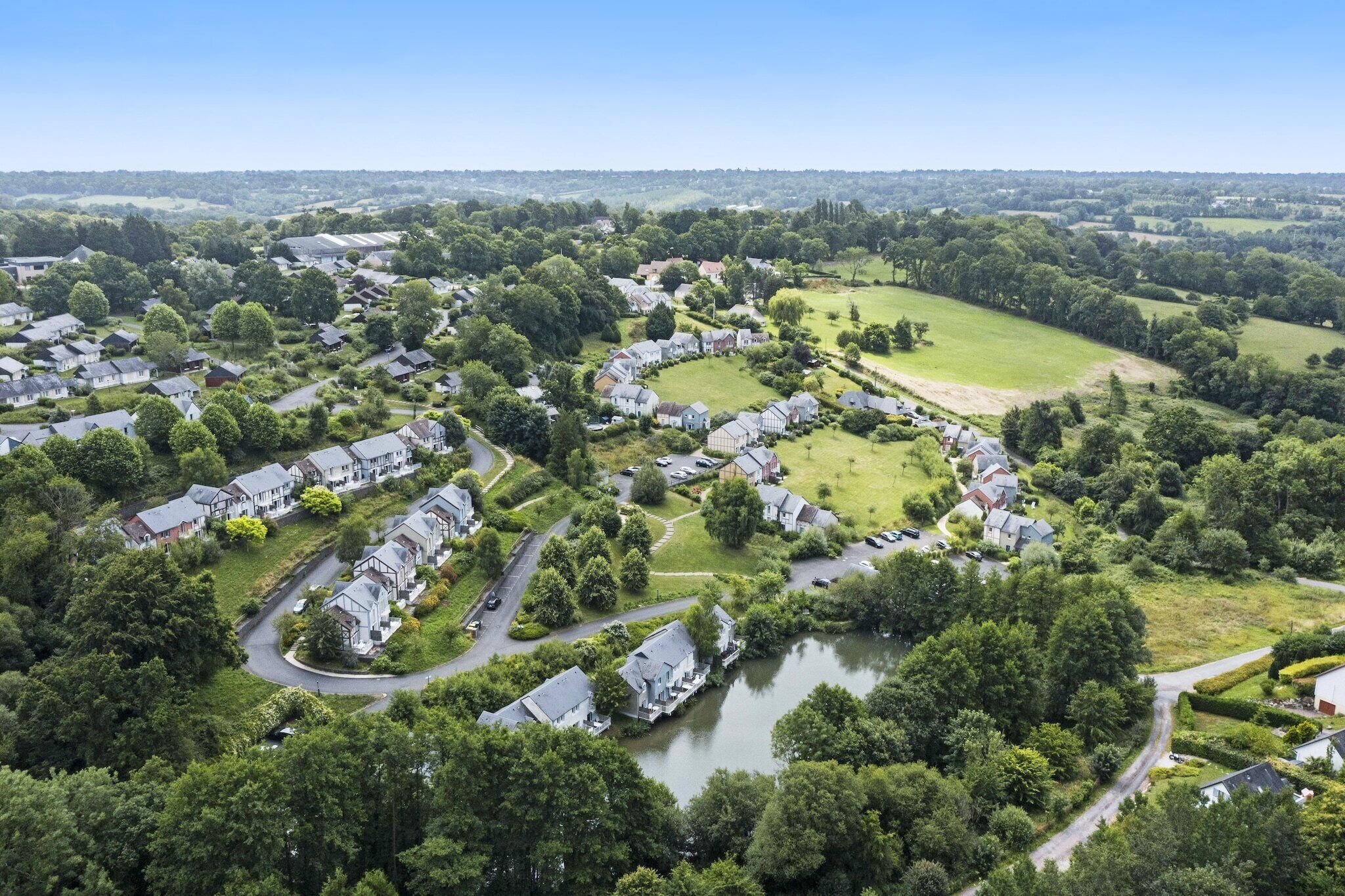 Vista aérea de una zona residencial con casas, un lago y vegetación circundante.