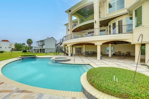 A two-story building with a swimming pool, outdoor seating, and a covered patio area.