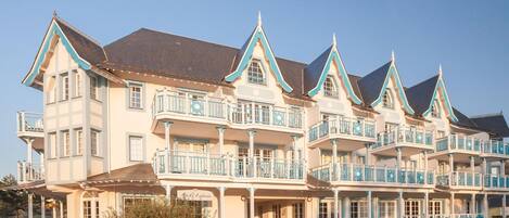 A large, multi-story building with balconies and a covered entrance.