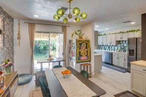 Eine moderne Küche mit weißen Schränken, einem Edelstahlkühlschrank und einem Essbereich mit Holztisch und Stühlen.