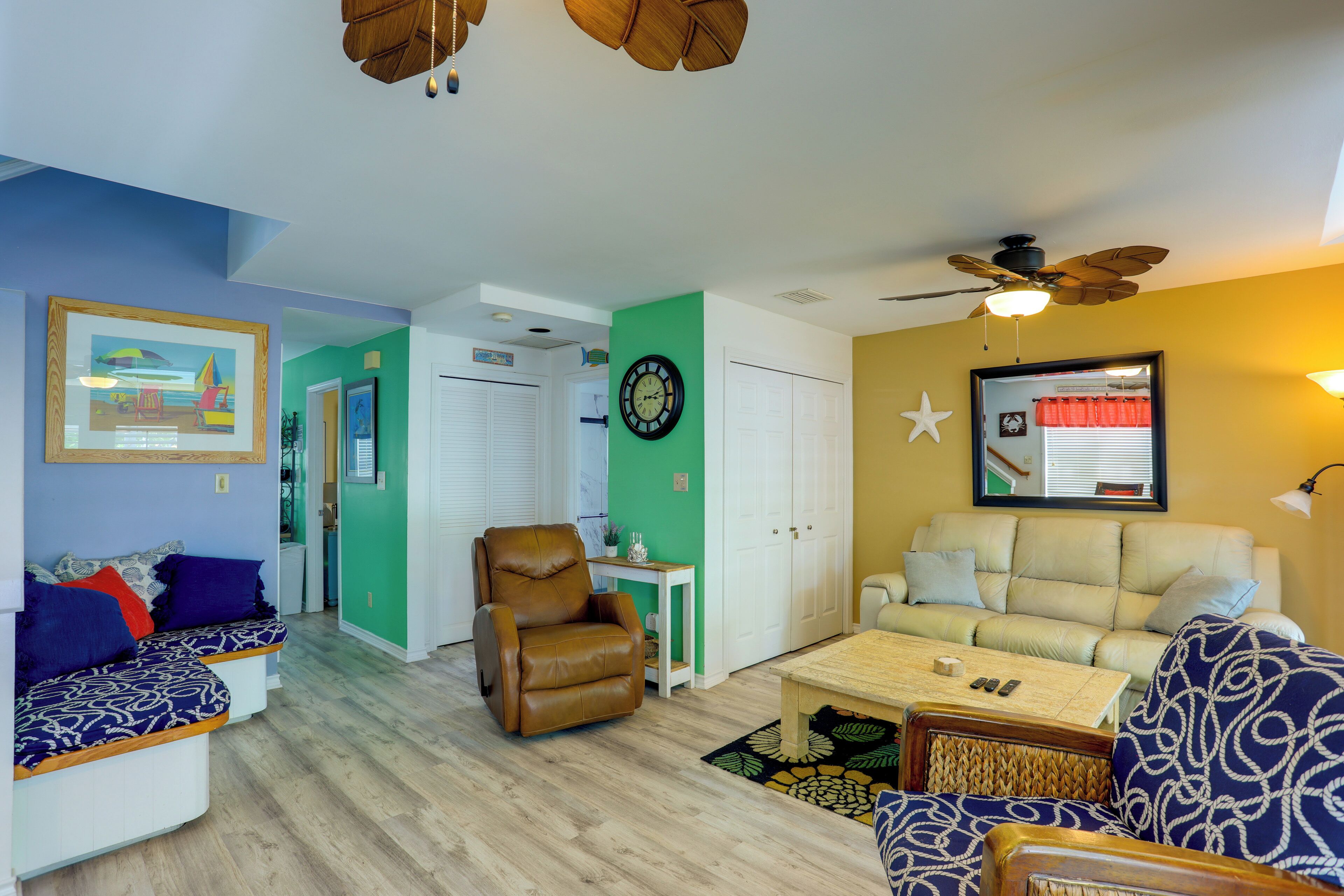 A living room with a brown leather chair, a beige sofa, a wooden coffee table, and a ceiling fan.