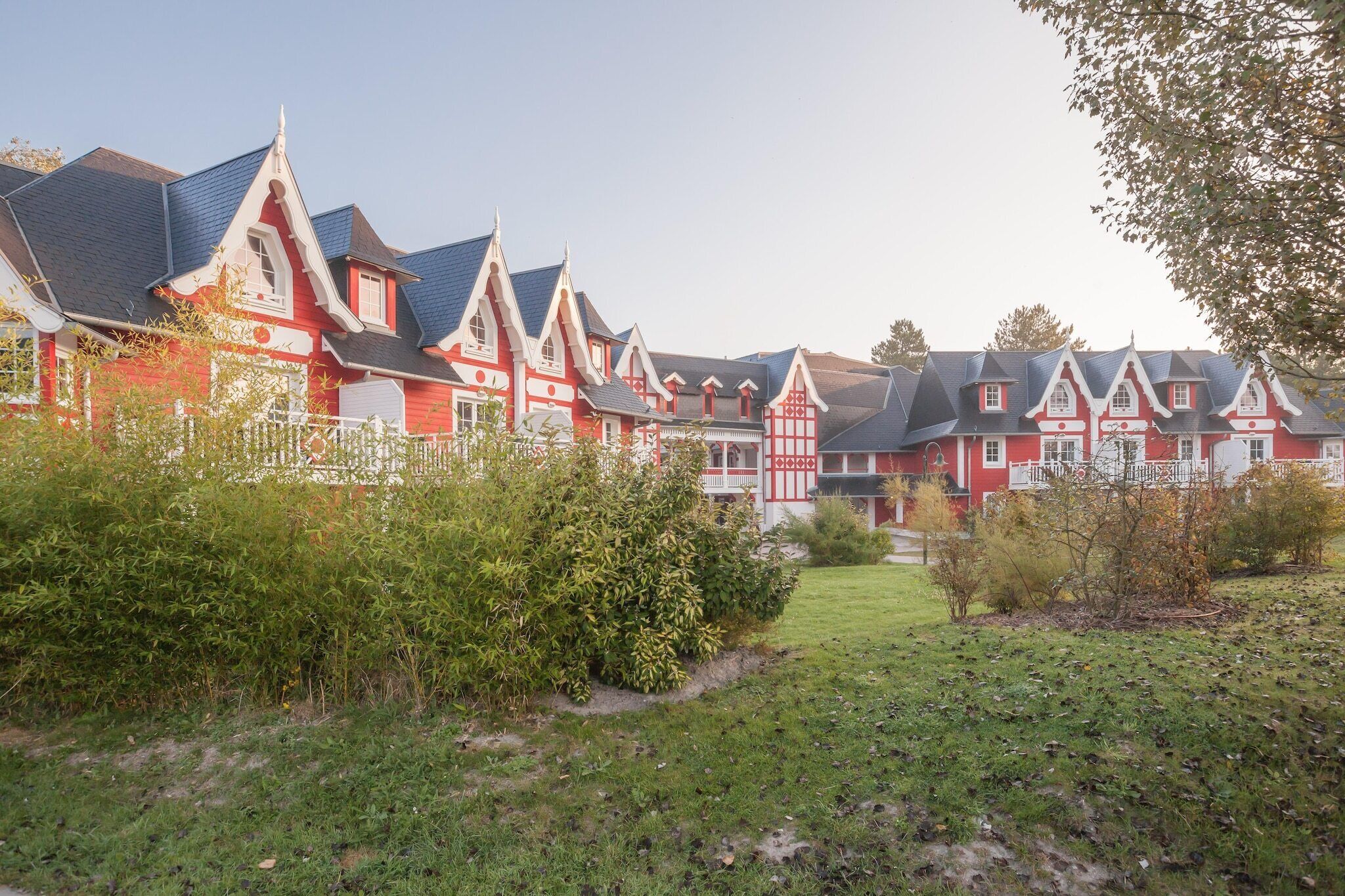 A row of red and white houses with steeply pitched roofs and white trim.