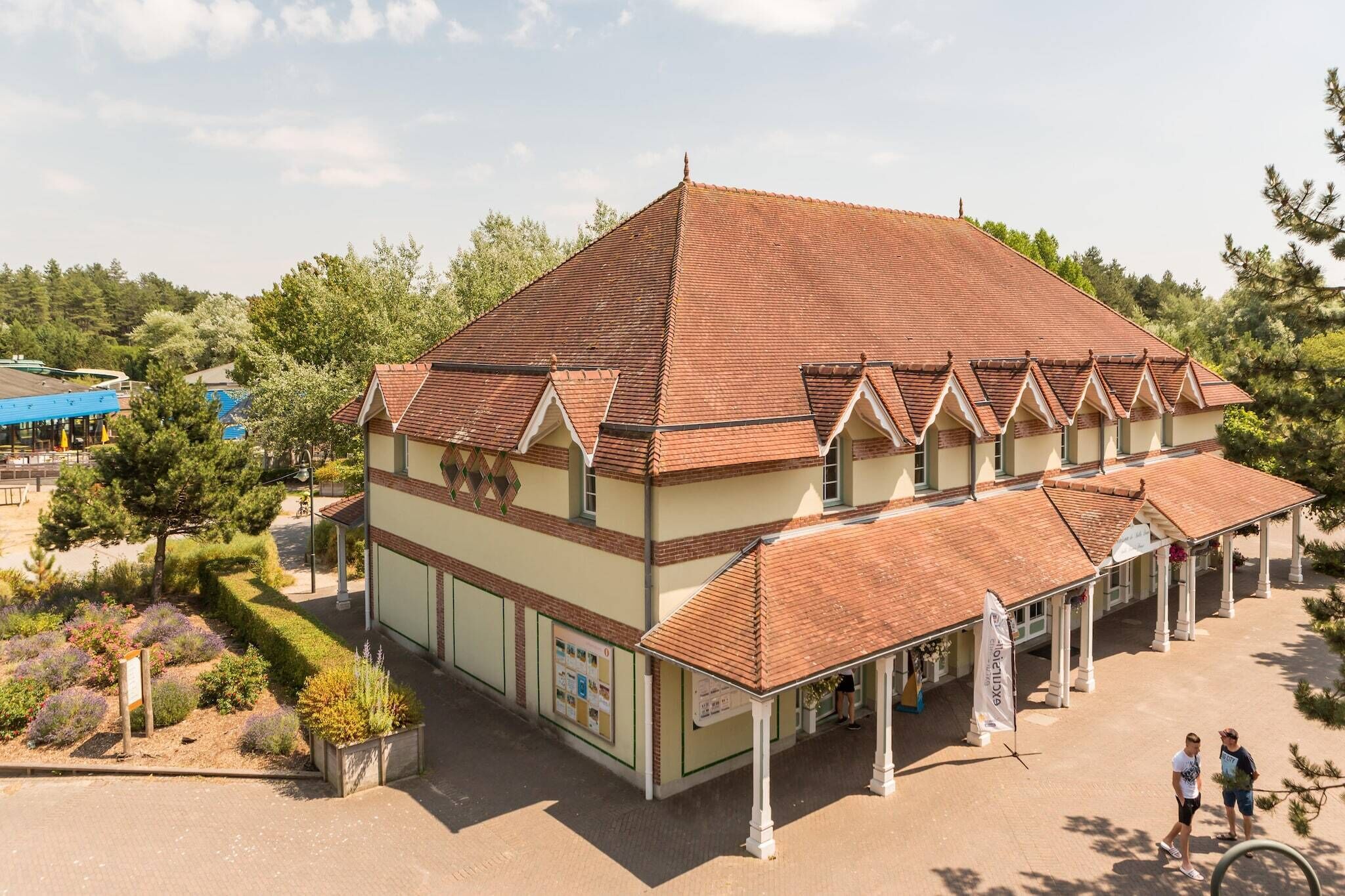 A building with a tiled roof, a covered walkway, and a landscaped garden.