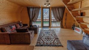 A wooden cabin interior with a sofa, a rug, a Christmas tree, and a staircase. - Welcome to our property ❤️ Cozy house in mountains (Stepantsminda)