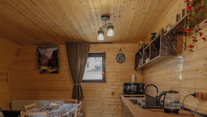 A wooden interior with a dining area, kitchen, and a patterned rug. - Welcome to our property ❤️ Cozy house in mountains (Stepantsminda)