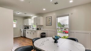 A modern kitchen with white cabinets, a marble countertop, and a dining area with a round table and chairs. - Easy Access to Dtwn & Fort Benning: Family Home (Columbus)