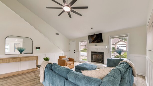 A modern living room with a sectional sofa, a fireplace, a ceiling fan, and a large mirror. - Easy Access to Dtwn & Fort Benning: Family Home (Columbus)
