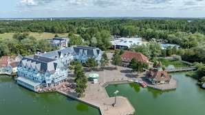 Ein Hotel am Seeufer mit Steg, einem kleinen Boot und einem Pavillon.