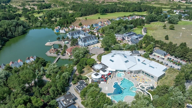 Eine Vogelperspektive zeigt ein Resort mit einem großen Schwimmbad, einem Golfplatz und einem See.