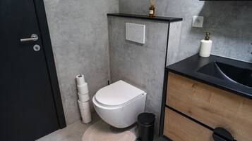 Een moderne badkamer met toilet, wastafel en opbergkast.