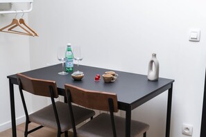 Een eettafel met stoelen, een waterfles, een glas, een vaas en een klein rood voorwerp.