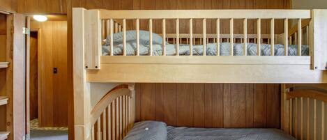 A bunk bed with a wooden headboard and a lower bed with a quilted mattress.