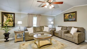 A living room with a ceiling fan, two sofas, a coffee table, and two lamps. - The Quiet Escape… Near New Orleans (LaPlace)