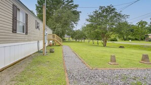 A single-story house with a covered porch, a gravel pathway, and a grassy yard. - The Quiet Escape… Near New Orleans (LaPlace)