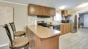 A kitchen with wooden cabinets, a central island, a microwave, and a refrigerator. - The Quiet Escape… Near New Orleans (LaPlace)
