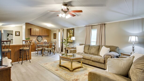 A living room with a sofa, coffee table, and chairs. There is a dining area with a table and chairs. A ceiling fan is visible. - The Quiet Escape… Near New Orleans (LaPlace)