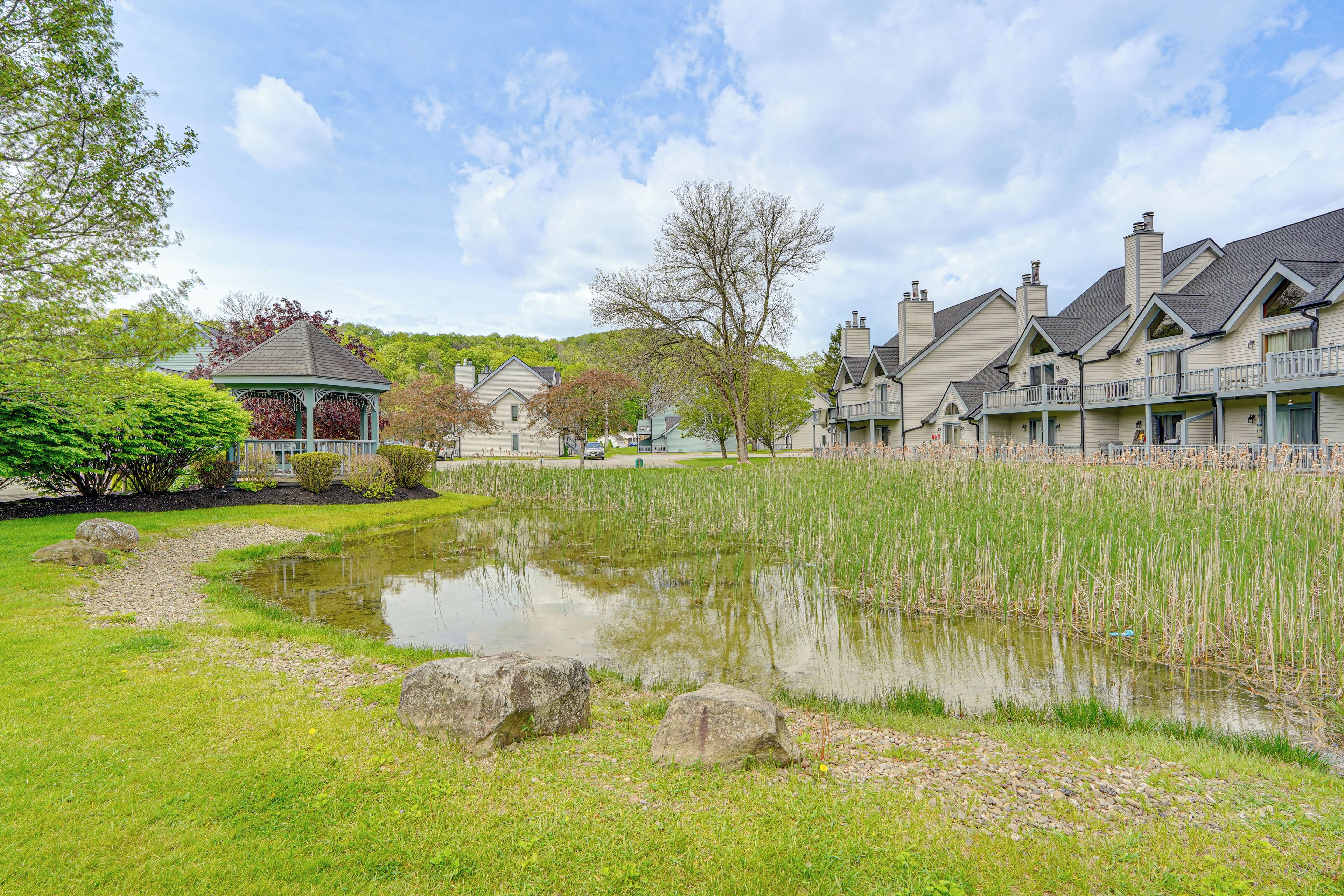 A residential area with a pond, a gazebo, and houses with balconies.
