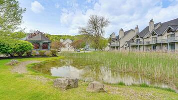 A residential area with a pond, a gazebo, and houses with balconies.
