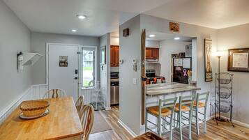 A modern kitchen with a central island, wooden dining table, and chairs.