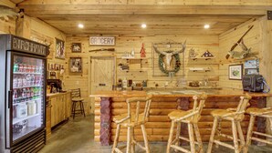Uma área de bar rústica com geladeira, banquetas e uma placa indicando a seção de mantimentos.