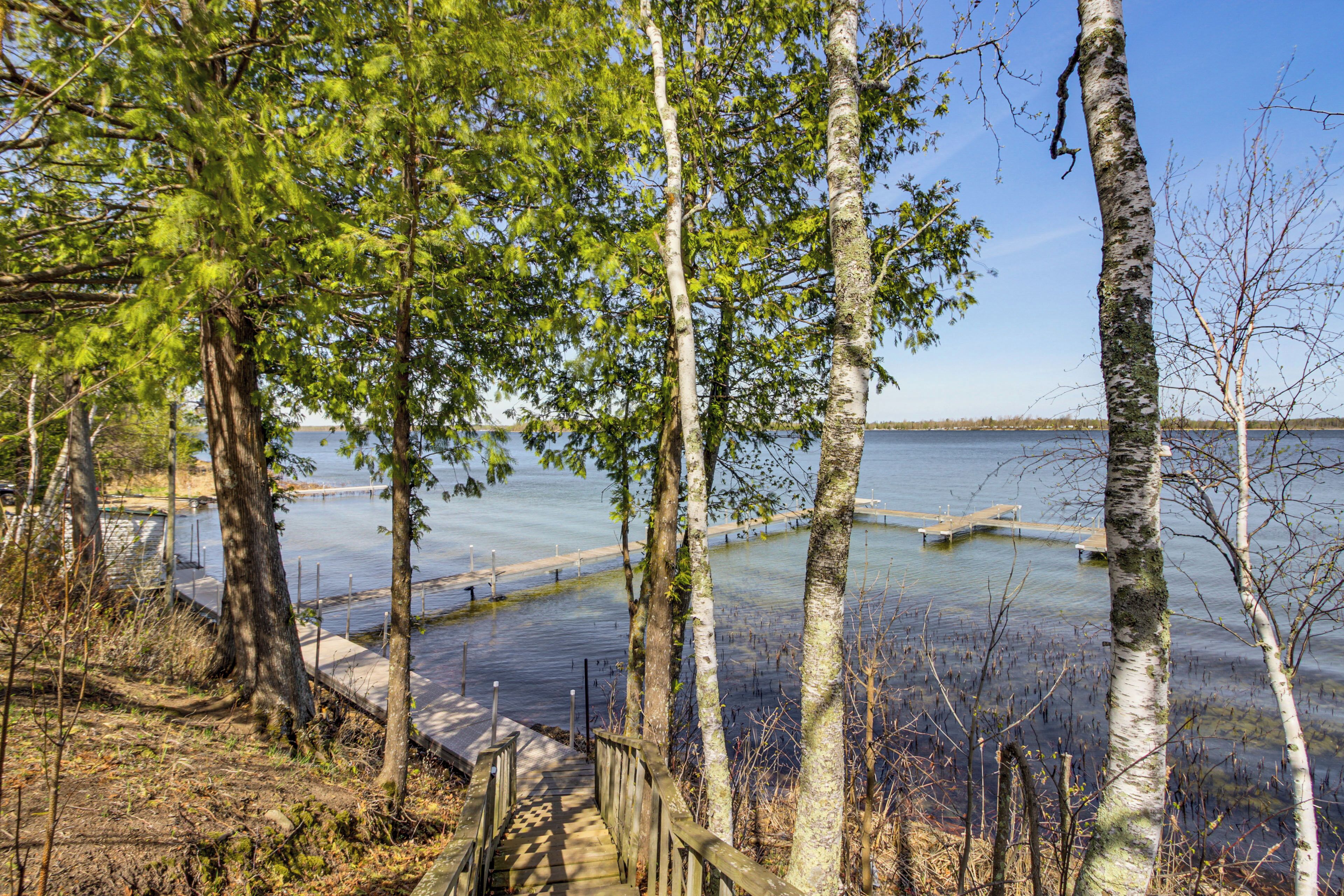 Puinen kävelytie johtaa laiturille, joka on rakennettu tyynen järven ylle, ja sen ympärillä on puita.