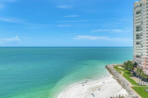 Ein hoch aufragendes Hotel mit Blick auf den Strand, einem gepflegten Rasen und blauem Himmel.