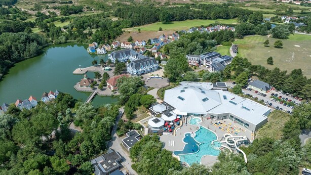 An aerial view of a resort with a large swimming pool, a golf course, and a body of water. - House with Terrace Overlooking the Lake (Fort Mahon Plage)