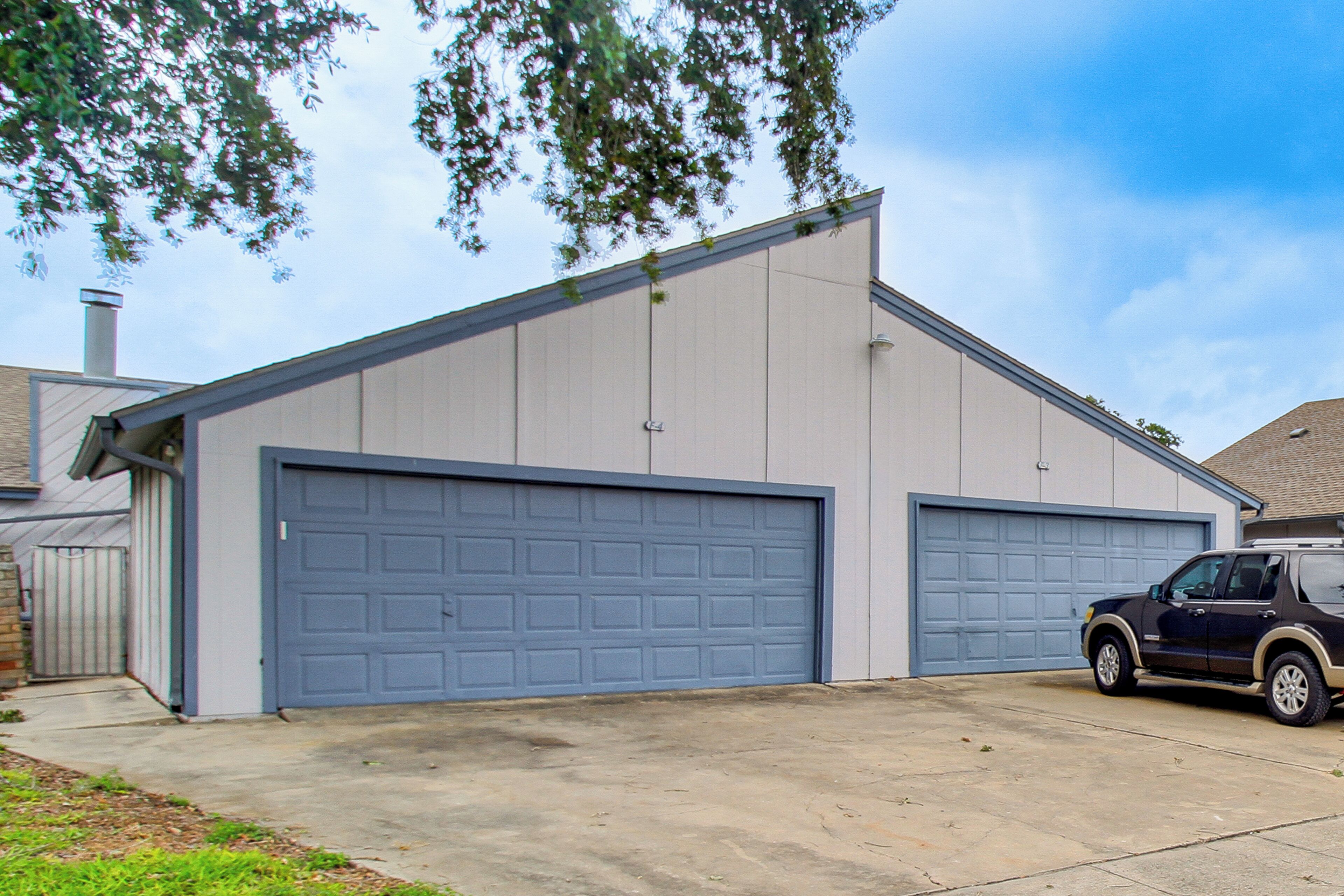 A two-story building with a garage and a parked SUV.