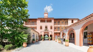 A building with a clock tower, arched walkways, and potted plants. - Ardèche House with Spacious Terrace for 8 (Grospierres)